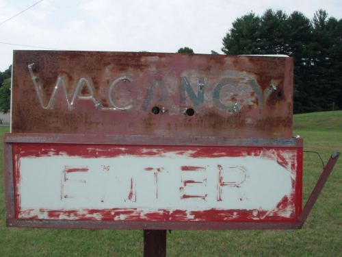 An old sign stating that there is a vacancy at the hotel it appears in front of.