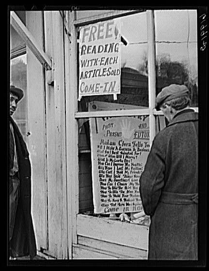 Two men outside a fortune teller's shop, with a sign advertising a free reading with every article sold.